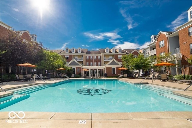 community pool with a patio, fence, and a residential view