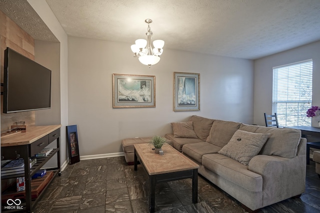 living room featuring a notable chandelier, baseboards, and a textured ceiling