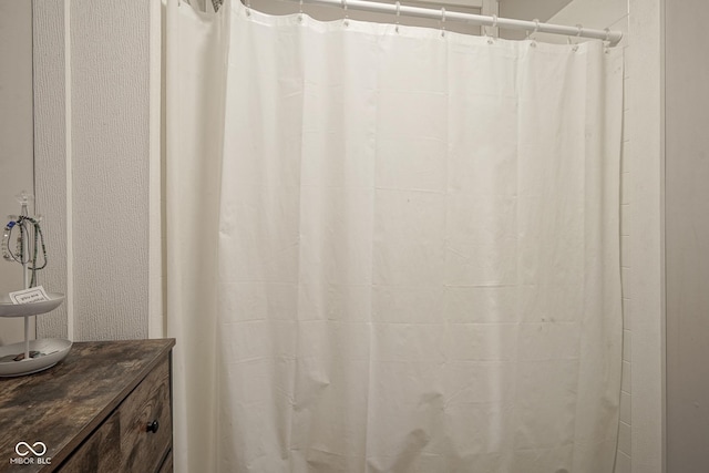 full bathroom featuring a shower with shower curtain and a textured wall