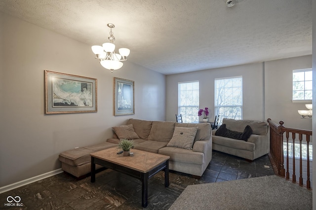 living room featuring a textured ceiling, stone finish floor, baseboards, and a chandelier