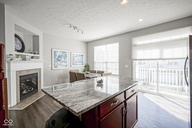 kitchen with light stone counters, a textured ceiling, dark wood-style flooring, and a fireplace