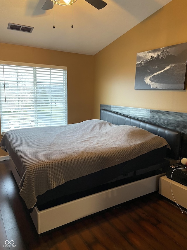 bedroom with dark wood-style flooring, visible vents, vaulted ceiling, and ceiling fan