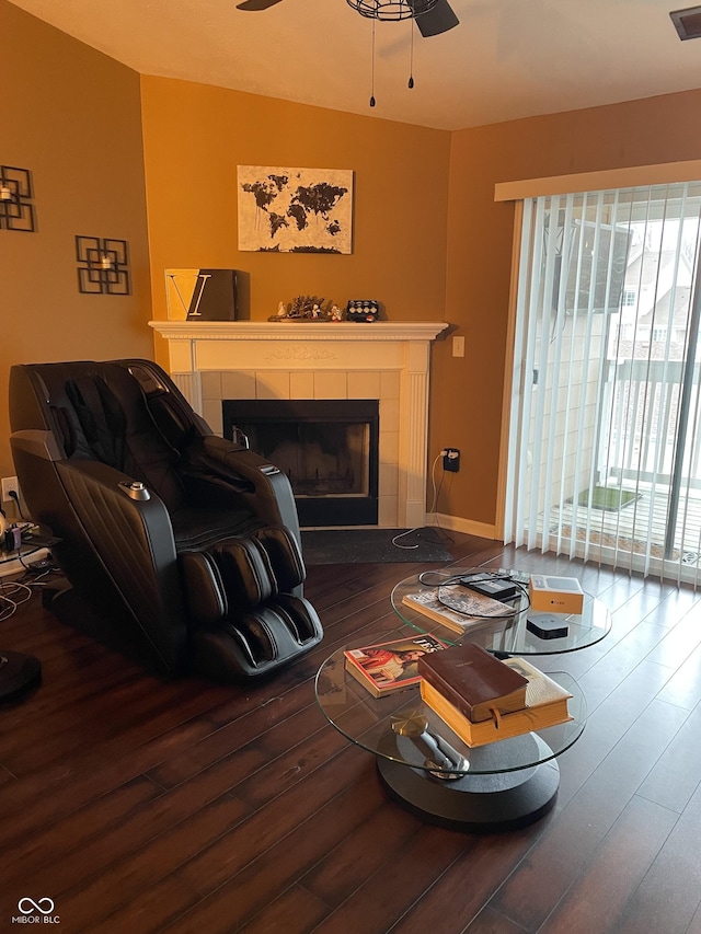 living area featuring a fireplace, wood finished floors, visible vents, a ceiling fan, and baseboards