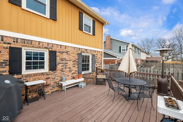 deck featuring outdoor dining area, a grill, and fence