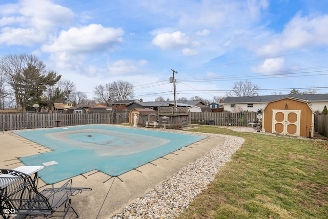 view of pool with a yard, a fenced backyard, a storage unit, and an outbuilding