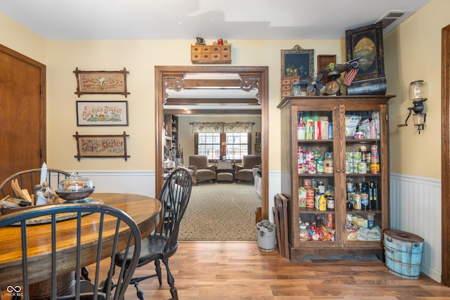 dining area featuring wainscoting, wood finished floors, and visible vents