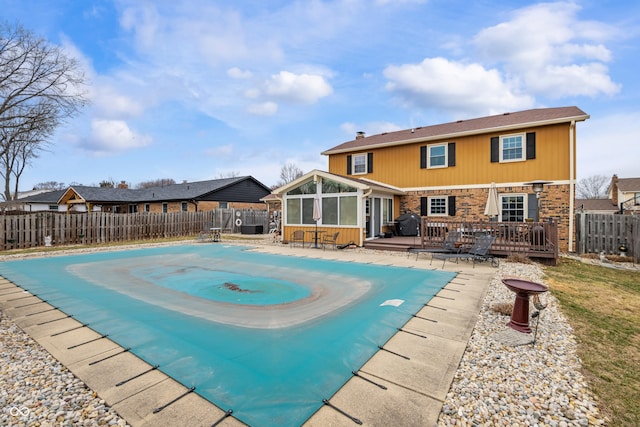 view of swimming pool with a sunroom, a fenced backyard, grilling area, and a wooden deck