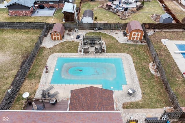 view of pool featuring a storage shed, an outdoor structure, and a fenced backyard