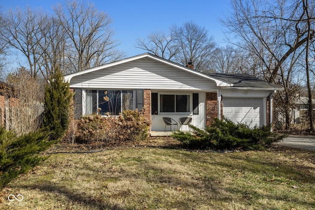 view of front of house with a front yard, brick siding, a chimney, and an attached garage