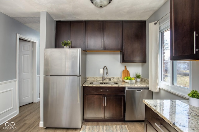 kitchen with dark brown cabinetry, stainless steel appliances, and a sink