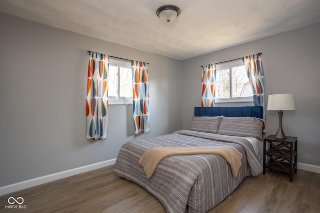 bedroom with baseboards, multiple windows, and wood finished floors