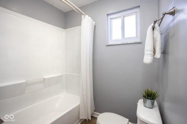 bathroom featuring toilet, baseboards, and shower / bathtub combination with curtain