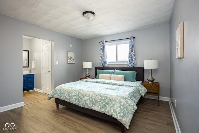 bedroom featuring baseboards, ensuite bath, and light wood finished floors