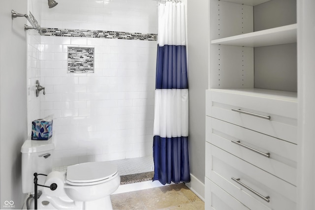 bathroom featuring tiled shower and toilet