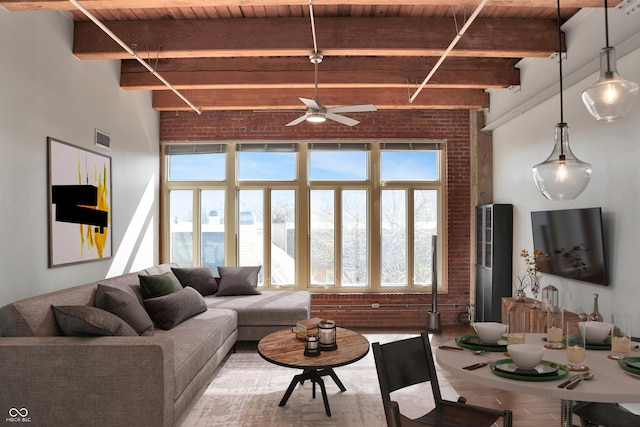 living area featuring visible vents, a high ceiling, wood ceiling, brick wall, and beamed ceiling