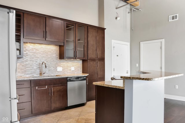 kitchen featuring visible vents, freestanding refrigerator, a sink, light stone countertops, and dishwasher