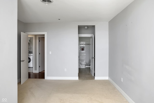 unfurnished bedroom featuring visible vents, baseboards, stacked washer and clothes dryer, ensuite bath, and carpet