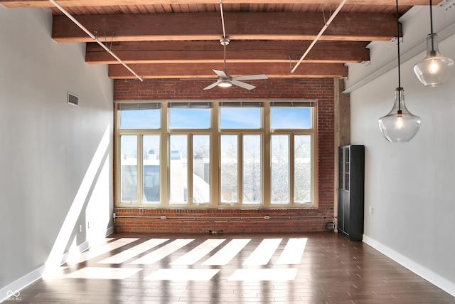 unfurnished living room featuring brick wall, dark wood-style flooring, beam ceiling, and baseboards