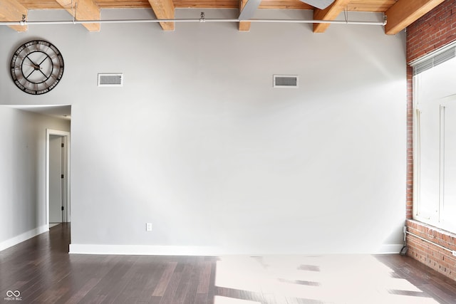 empty room featuring visible vents, beamed ceiling, and wood finished floors