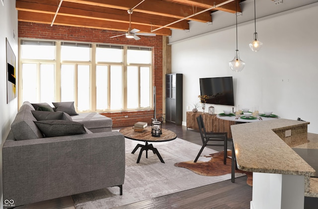 living room with a ceiling fan, beam ceiling, dark wood finished floors, and brick wall