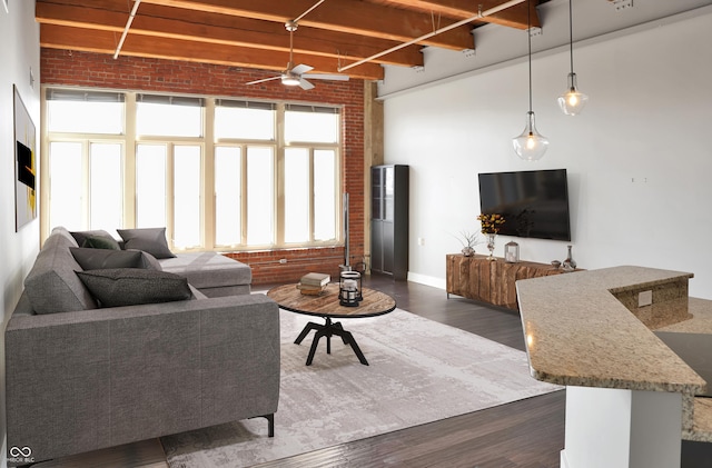 living area with ceiling fan, brick wall, dark wood-style flooring, baseboards, and beamed ceiling