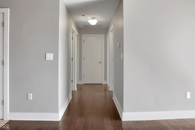 corridor featuring baseboards and wood finished floors