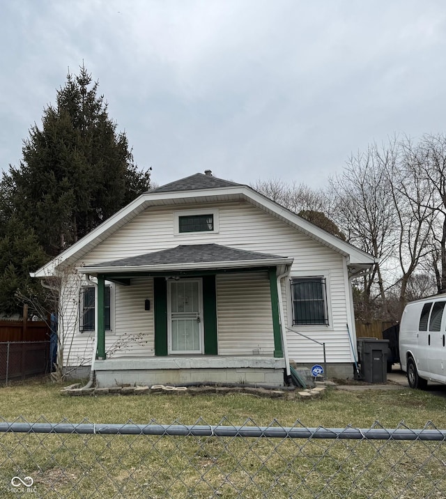 bungalow with a shingled roof, fence, a porch, and a front yard