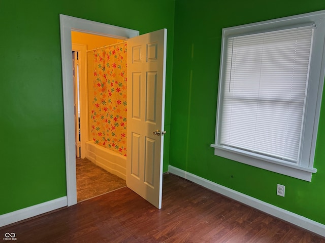 unfurnished bedroom with baseboards and dark wood-style flooring