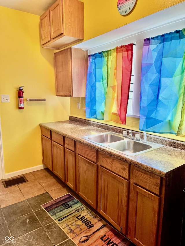 kitchen with brown cabinets, visible vents, a sink, and baseboards