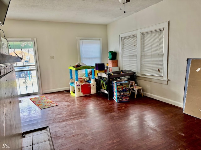 interior space with a textured ceiling, baseboards, and wood finished floors