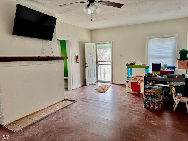 foyer entrance with a textured ceiling, ceiling fan, wood finished floors, and baseboards