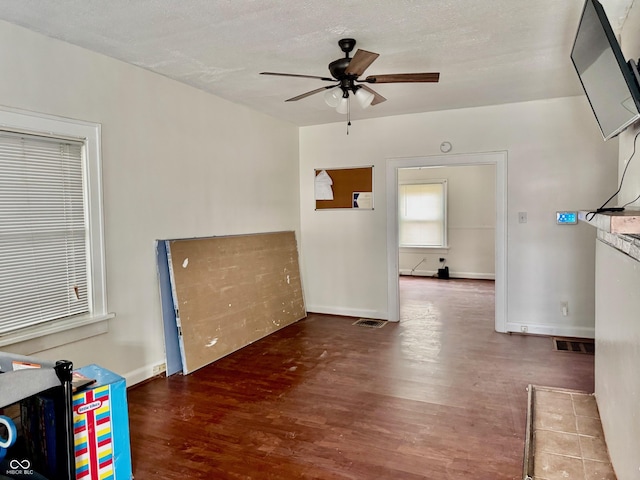 interior space with visible vents, ceiling fan, baseboards, and wood finished floors