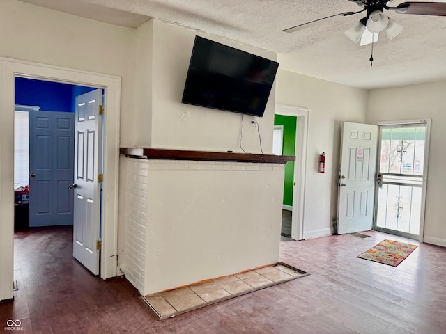 entrance foyer with baseboards, a textured ceiling, a ceiling fan, and wood finished floors