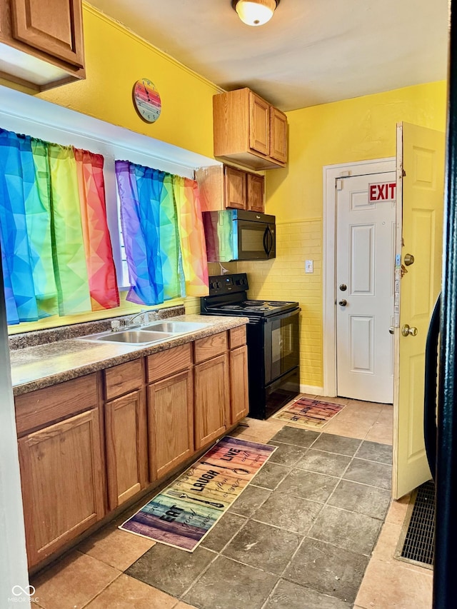 kitchen with black appliances, brown cabinetry, and a sink