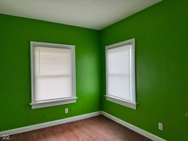 unfurnished room with dark wood finished floors and baseboards