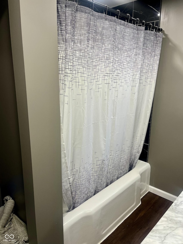 bathroom with baseboards, shower / bath combination with curtain, and wood finished floors