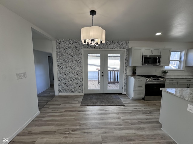 kitchen featuring light stone counters, french doors, light wood finished floors, appliances with stainless steel finishes, and baseboards