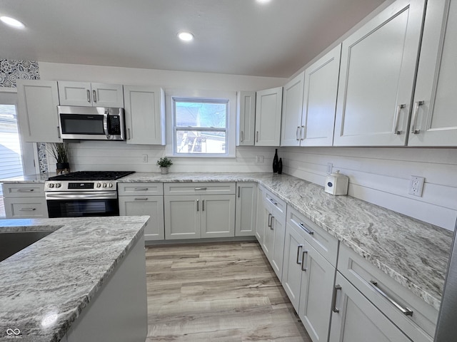 kitchen featuring light wood-type flooring, light stone counters, stainless steel appliances, and recessed lighting