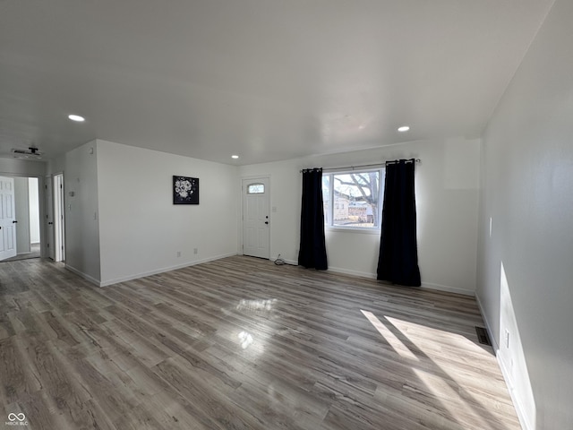 empty room featuring baseboards, wood finished floors, and recessed lighting