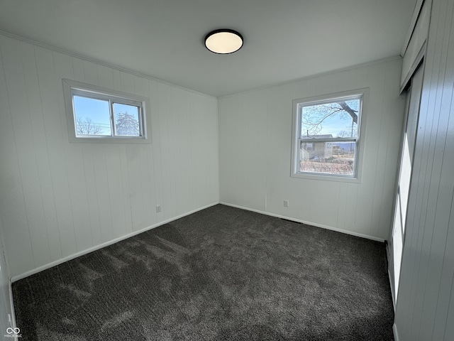 unfurnished bedroom with multiple windows, baseboards, and dark colored carpet