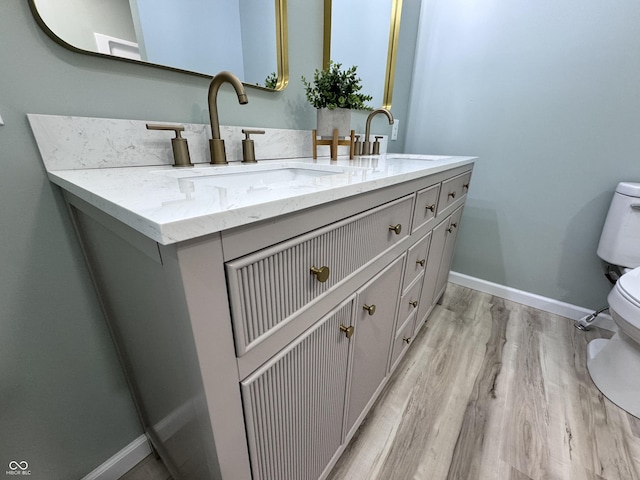 bathroom with double vanity, a sink, toilet, and baseboards