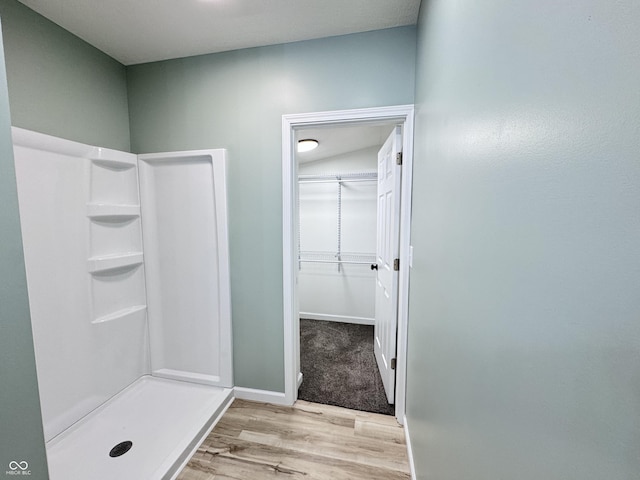 bathroom featuring a stall shower, baseboards, and wood finished floors