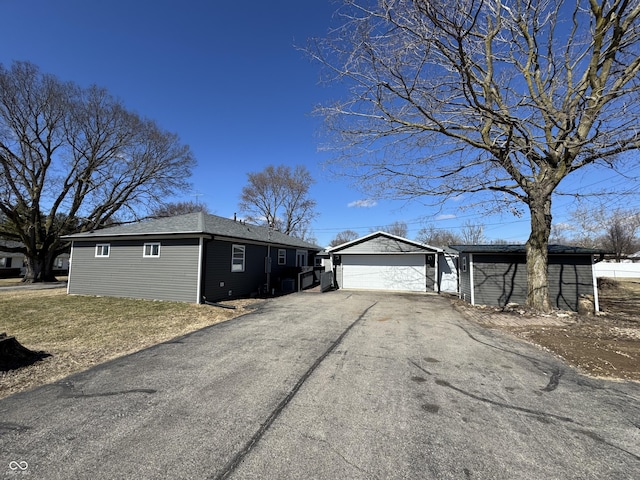 view of front of property featuring driveway, a garage, and an outbuilding