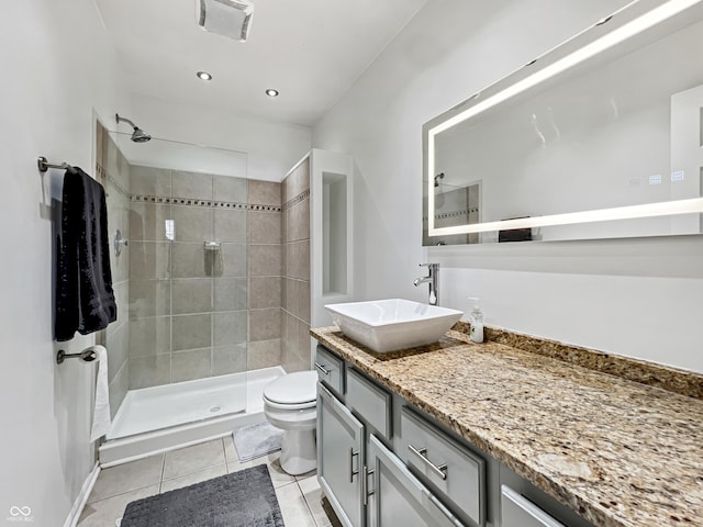 bathroom featuring vanity, tile patterned floors, toilet, and a tile shower