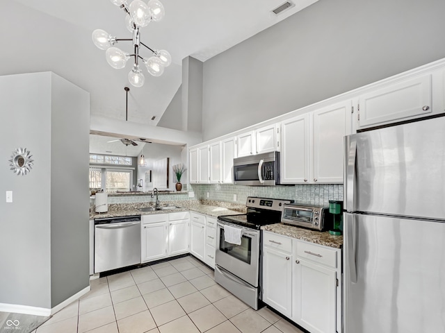 kitchen with visible vents, a sink, backsplash, stainless steel appliances, and light stone countertops