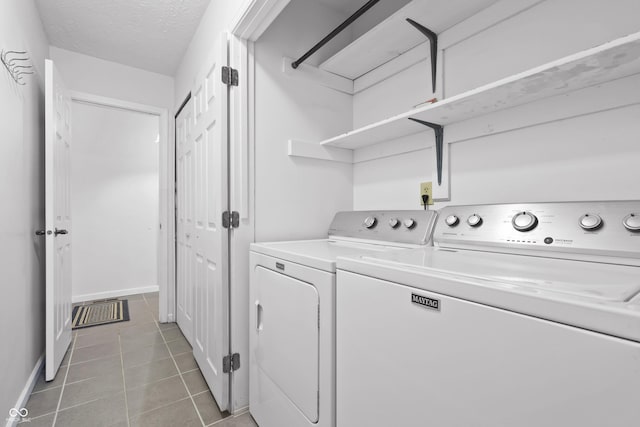 laundry area featuring laundry area, baseboards, tile patterned flooring, a textured ceiling, and washing machine and dryer