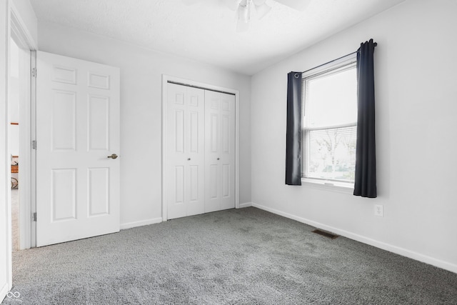 unfurnished bedroom featuring baseboards, a ceiling fan, a textured ceiling, carpet flooring, and a closet