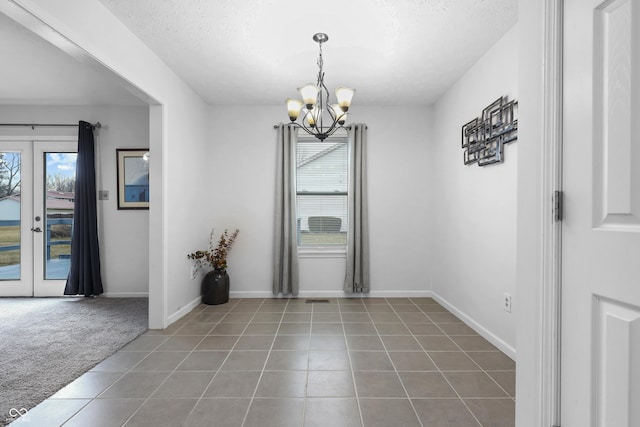 unfurnished dining area with an inviting chandelier, tile patterned flooring, carpet flooring, and french doors