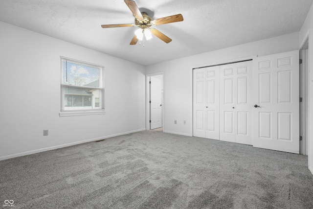 unfurnished bedroom with baseboards, ceiling fan, carpet, a textured ceiling, and a closet