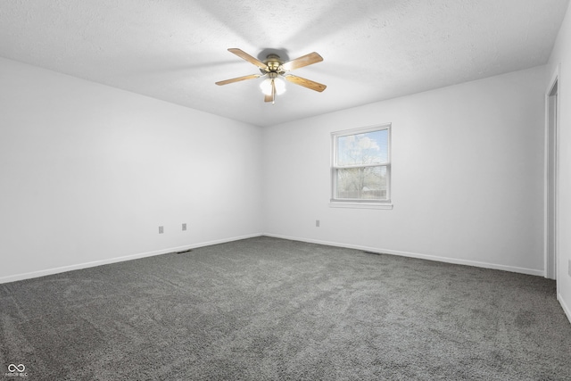 empty room featuring a textured ceiling, dark carpet, a ceiling fan, and baseboards